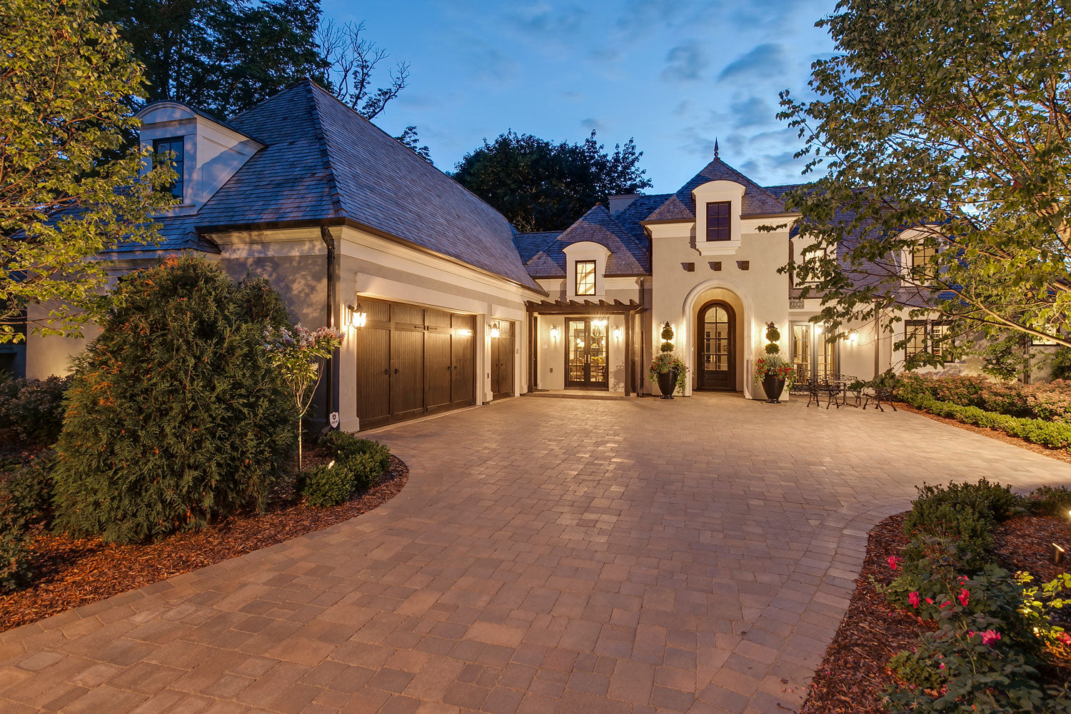 Beautiful custom home, courtyard driveway and 3 car garage at dusk