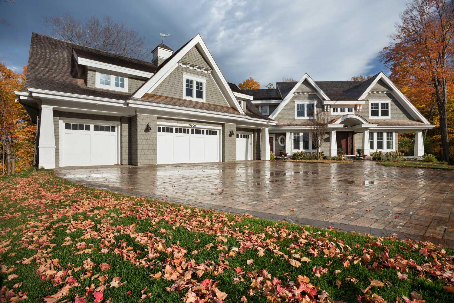 Large custom home with craftsman details, a 4 car garage and paver stone driveway.