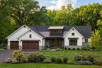 Modern Ranch style home with a black roof and white walls, surrounded by trees and flowers.