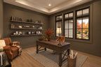 Home office with dark taupe walls, a wood desk, floating shelves and a leather armchair beneath a tray ceiling.