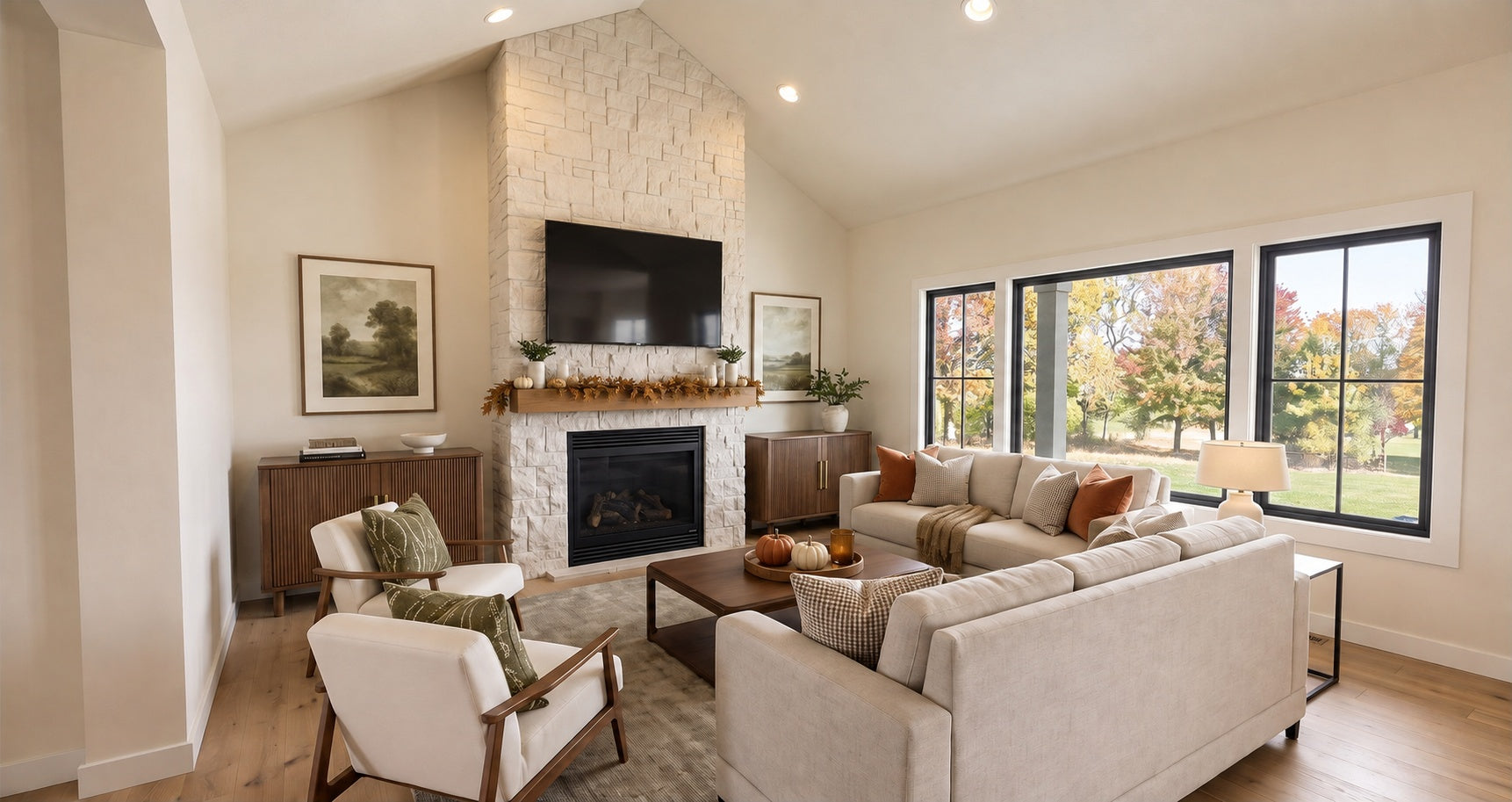 Alder Glen vaulted great room with a floor-to-ceiling stone fireplace, neutral sofas and large rear-facing windows.