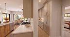 Alder Glen kitchen cooktop and stone counters beside the prep kitchen entry, with the dining area visible beyond the island.