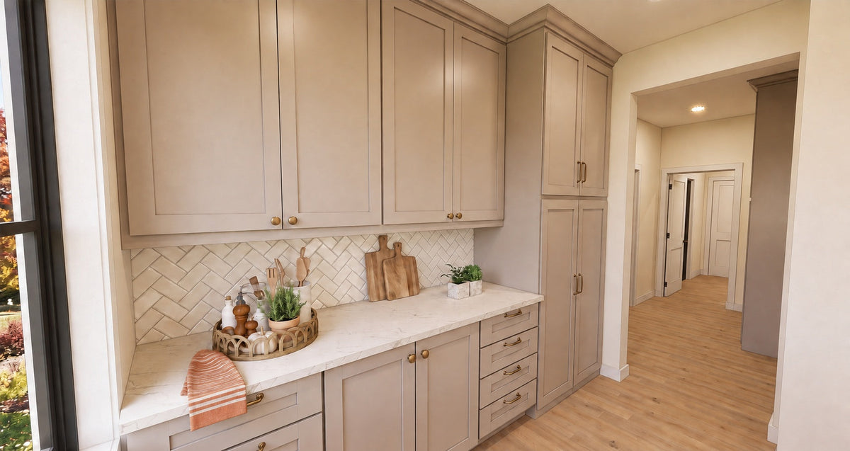 Alder Glen prep kitchen with gray cabinets, a pale countertop, brass knobs and a herringbone tile backsplash.