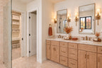 Primary bathroom with a wood double vanity, framed mirrors, wall sconces and open linen shelving.
