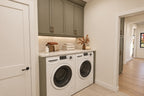 Laundry area with a side-by-side washer and dryer, a folding counter and gray wall cabinets.