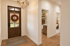 Foyer with an autumn wreath on the glazed wood front door and views into the powder room and bedroom hallway.