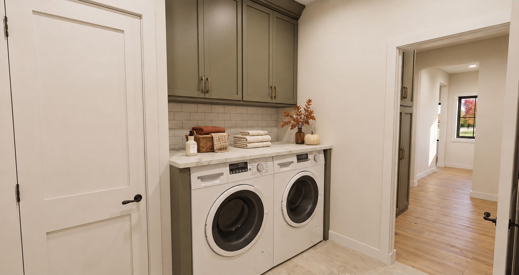 Alder Glen laundry area with a side-by-side washer and dryer, a folding counter and gray wall cabinets.