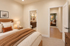 Front bedroom with warm neutral bedding and views through the shared bathroom and bedroom hallway.
