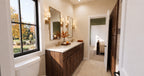 Alder Glen Jack and Jill bathroom with a dark wood double vanity, brass sconces and a doorway to the green-walled bedroom.