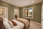 Rear bedroom with muted green walls, an upholstered bed and openings to the hallway and shared bathroom.