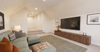 Alder Glen bonus room with a green sectional facing a television and wood console, beside steps to the entry landing.
