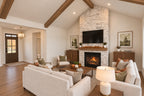 Great room facing the stone fireplace with cream seating and a view of the wood front door in the foyer.