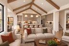 Great room looking past cream sofas toward the kitchen island, pendant lights and vaulted wood-beam ceiling.