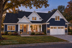 Willow Cove front exterior at dusk with illuminated windows, navy siding, a covered porch and a white garage door.