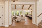 Willow Cove foyer opening to the great room and kitchen, with exposed wood beams and a staircase on the right.