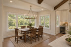 Willow Cove dining room with a rectangular wood table, wood chairs and a candle-style chandelier beside windows on two sides.