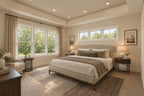 Willow Cove primary bedroom with neutral bedding, an upholstered bed, a tray ceiling and large windows overlooking leafy trees.