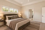Willow Cove primary bedroom with neutral bedding and high windows above the bed, looking toward the adjoining bathroom.