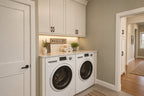 Willow Cove laundry area with a front-loading washer and dryer, white upper cabinets, a folding counter and a doorway to the hall.