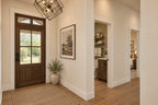 Willow Cove foyer with a wood-and-glass front door, geometric pendant and views into the powder room and bedroom hallway.
