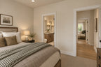 Willow Cove front bedroom with neutral bedding and a green checked throw, looking toward the shared bathroom and hallway.