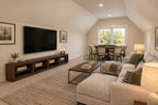 Willow Cove bonus room with a cream sectional, wall-mounted television, wood media console and a game table beneath the far window.