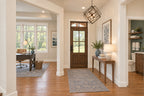 Oak Haven foyer with a wood-and-glass front door, geometric pendant light and an open doorway to the home office.