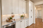 Oak Haven prep kitchen with light cabinetry, a herringbone backsplash, countertop storage and an open doorway to the hallway.