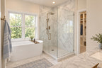Oak Haven primary bathroom with a freestanding tub beneath a large window, a glass shower and an adjoining storage area.