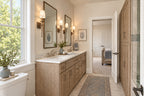 Oak Haven Jack and Jill bathroom with a wood double vanity, two mirrors, wall sconces and a large window.