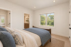 Oak Haven rear bedroom with light walls, blue and cream bedding and open doorways to the shared bathroom and hallway.