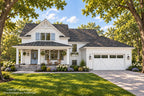 Farmhouse front exterior with white siding, blue shutters, a covered porch and a two-car garage.