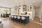 Kitchen with a blue island, four stools, white cabinetry and black pendant lights.