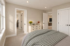 Upstairs bedroom with patterned bedding, a dresser and access to the shared bathroom.