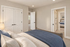 Upstairs bedroom with blue bedding, double closet doors and an adjoining bathroom.
