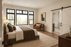 Main-level primary-bedroom rendering with a large window and a sliding bathroom door.