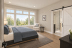 Primary bedroom with blue bedding, wide windows and a white sliding barn door to the bathroom.