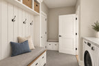 Mudroom and laundry with a built-in bench, coat hooks, upper storage and a washer beneath the counter.
