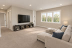 Upstairs loft lounge with a sectional, television console and windows overlooking the yard.