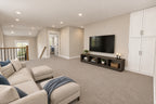Loft seating and television area beside the stair railing, bedroom doors and built-in storage.
