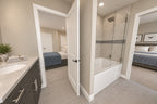 Upstairs bathroom with a dark vanity, glass shower and a view into the adjoining bedroom.