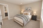 Upstairs bedroom with a neutral upholstered bed, dark nightstands and a side window.