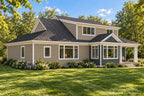 Rear-left exterior if this farmhouse style home with a broad upper dormer, green dining-room gable, taupe siding and a covered back porch.