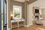 Foyer with a console table beneath a window, opening to the great room with its stone fireplace.
