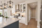 Kitchen range and hood between white cabinets, with the island in front and pantry entry beside the cooking area.