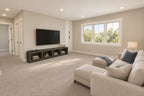 Upstairs loft lounge with a sectional, television console and windows overlooking the yard.