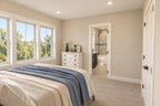 Upstairs bedroom with blue bedding, three tall windows and an adjoining bathroom with a glass shower.