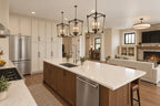 Kitchen island with a sink and wood cabinetry, looking toward the great room fireplace and entry hall.