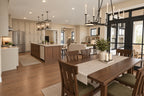 Window-lined dining area with a wood table and chandelier, connected to the kitchen island and great room.