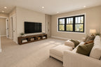Upstairs loft with a sectional sofa, television console, built-in storage and wide windows.